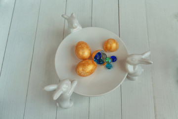 Beautiful painted multi-colored eggs for Easter on a white plate with hares