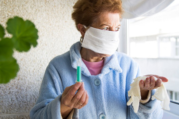 senior woman with mask and disposable medical gloves and syringe in one hand. concept of vaccine...