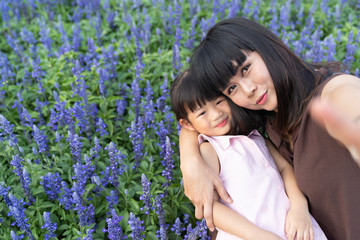 Asian mother with the beloved daughter in the blossoming lavender field.