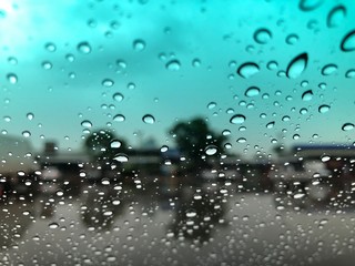 Rain falling on car windshield,drive car on street in city at heavy rain storm,blurred traffic light.