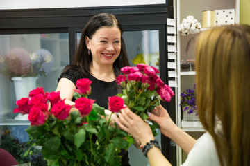 seller in the flower shop sells a bouquet of flowers to the buyer