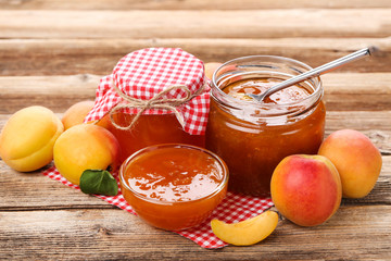Apricot jam in bowl and jar on brown wooden table