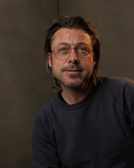 Studio portrait of a man wearing eyeglasses.