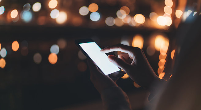 person texting text message on background blur color light night city, hipster touch on template screen, girls holding in hands smartphone mobile phone closeup, mockup blank screen