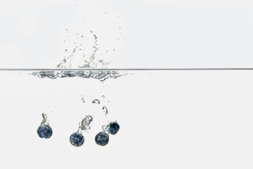 ripe blueberries splashing into transparent water