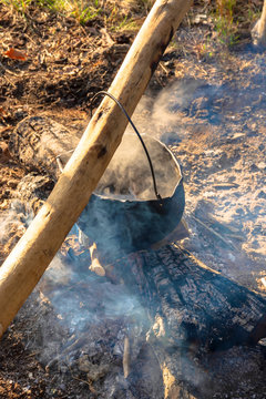 steaming old pot outdoor. cooking and camping. outdoor adventures concept. beaten cauldron on camp fire