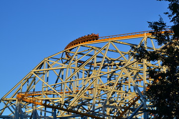 People having fun on roller coaster at outdoor amusement park. Yellow construction. Family holiday...