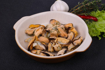 Pickled mussels in the bowl served pepper, garlic and salad
