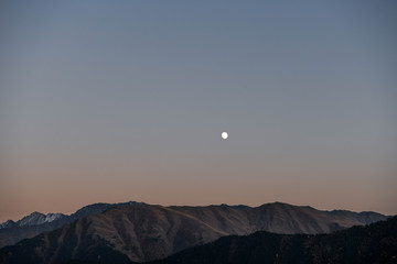 The moon rises over a mountain lit by the setting sun in the Tusheti region.
