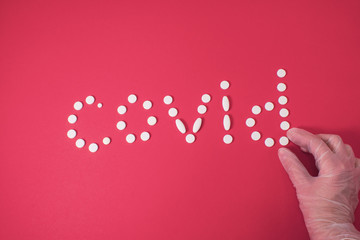 Covid pills inscription with hand in medical white transparent glove on pink background