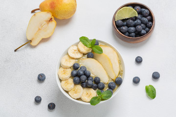 Healthy Breakfast smoothie in a bowl with banana, pear, kiwi, blueberry, lime and mint. The concept of healthy eating.