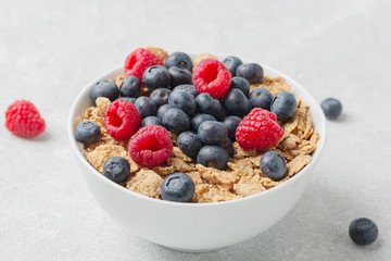 Multigrain wholewheat healthy cereals with fresh berry for breakfast. Bowl flakes with fresh berries raspberries and blueberries. 