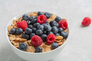 Multigrain wholewheat healthy cereals with fresh berry for breakfast. Bowl flakes with fresh berries raspberries and blueberries. 