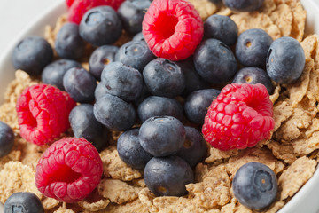 Multigrain wholewheat healthy cereals with fresh berry for breakfast. Bowl flakes with fresh berries raspberries and blueberries. Close up 