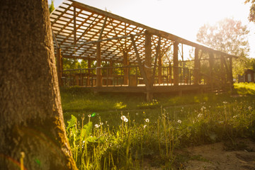 Wooden gazebo in nature in the Park for events. Sunlight through a grid of wooden beams-a game of chiaroscuro. Place for text and background