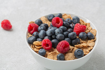 Multigrain wholewheat healthy cereals with fresh berry for breakfast. Bowl flakes with fresh berries raspberries and blueberries. 
