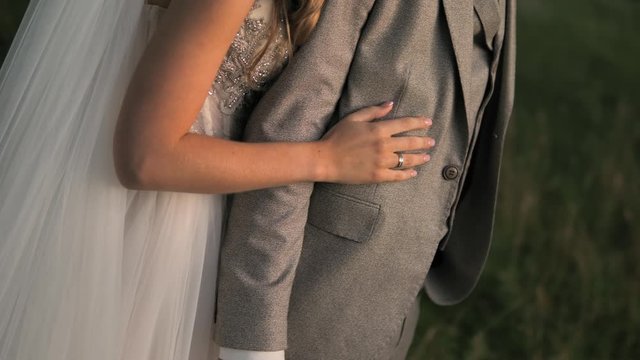 Wedding couple. The bride hugges the groom and takes his hand. Bride and groom embracing outdoors. Man and woman in love. Lovely groom and bride. Wedding day.   