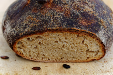A freshly baked loaf of bread has had the end sliced off it, there are a couple of pumpkin seeds in...