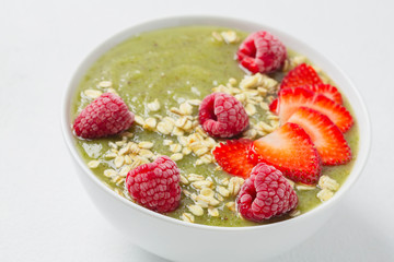 Breakfast green smoothie bowl with kiwi, banana, spinach, grapes, strawberries, raspberries and oatmeal. The concept of a detox diet.