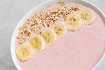Healthy breakfast berry smoothie bowl topped with banana, muesli and yogurt. Close up 