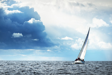 Sailing yacht regatta. Modern sailboat racing through the waves. Dramatic sky before the...