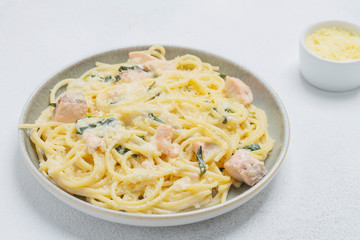 Spaghetti with salmon, cream cheese and spinach on plate. Italian cuisine. 