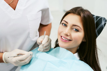 Dentist examining a patient's teeth in modern dentistry office. Closeup cropped picture with copyspace. Doctor in disposable medical facial mask.