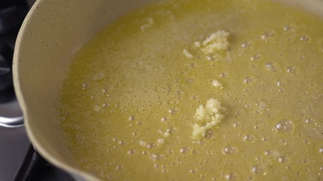 Putting garlic on melting butter in pan, close up shot. Garlic roasting and frying in the melted butter on the pan.