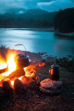 Lagerfeuer mit Kaffeekanne und Wasserkessel an einem Fluss in der Wildnis