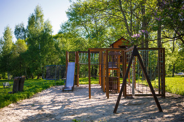 Fototapeta na wymiar Wooden children's Playground in nature in the eco-Park. Ladder, a swing, a Playhouse for children made of wood in rustic style