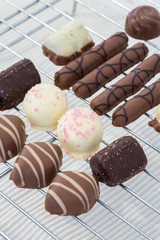 Selection of chocolates on a metal cooling rack.  On a cream ribbed towel background