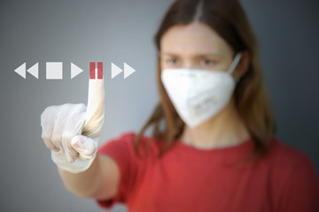 Woman in protective latex gloves and medical mask pressing pause button on the virtual screen. COVID 19 novel Coronavirus outbreak or air pollution concept.	