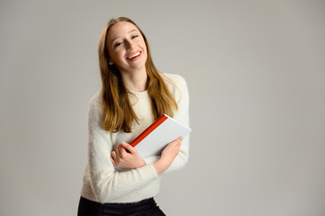 Studio portrait of a happy caucasian female student girl with a smile in a white sweater on a white background with a folder in hands