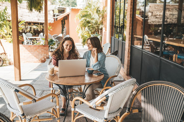 Two women discussing business projects in a cafe while having coffee.