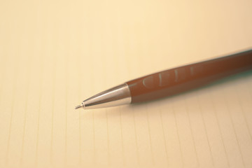 Vintage look of pen with yellow paper. Writing concept.