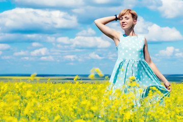 Obraz na płótnie Canvas young beautiful red haired woman on a blooming rapeseed field