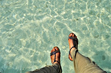 closeup image of woman feet in the beach of Maldives, Biyadhoo island, wearing sandal shoes