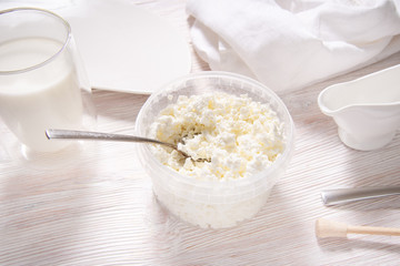 White cottage cheese in plastic jar on wooden table