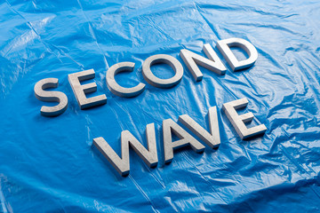 the words second wave laid with silver metal letters over crumpled blue plastic film background in...