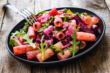 Pasta with beets and feta cheese on wooden table
