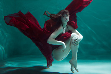beautiful girl in a red dress swims under water. amazing Underwater