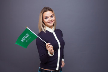 Immigration and the study of foreign languages, concept. A young smiling woman with a Saudi Arabia flag in her hand.