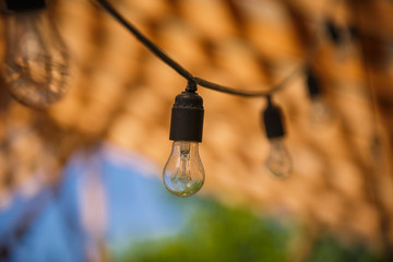 Garland of light bulbs in the loft style on a wooden background. Street lamp garland - incandescent lamp in the basement