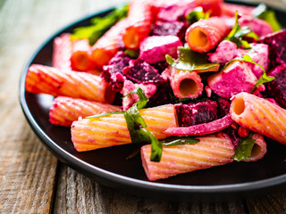 Pasta with beets and feta cheese on wooden table
