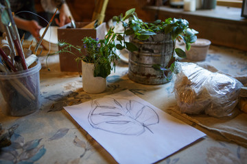 Drawing a pencil on a piece of paper sheet monstera. Arts & crafts, potted flowers and drawing