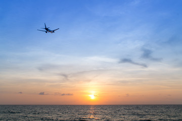 Fototapeta na wymiar airplane at sunset flying over ocean