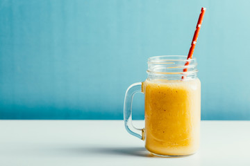 tasty mango smoothie in a glass jar on a blue background