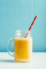 tasty mango smoothie in a glass jar on a blue background