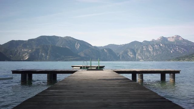 Empty wooden floating pier in mountain lake Attersee during sunny morning