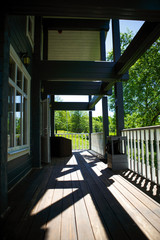View from the terrace of a country wooden house to the garden through the white wooden railing of the terrace. Verandah of a house in a Park in summer among trees and bushes